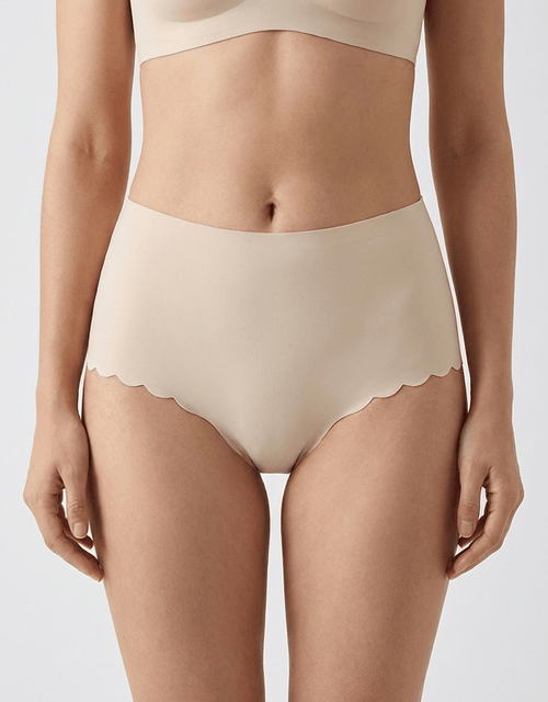 Seamless nude no-show panties with scalloped edges on a woman, invisible under clothing