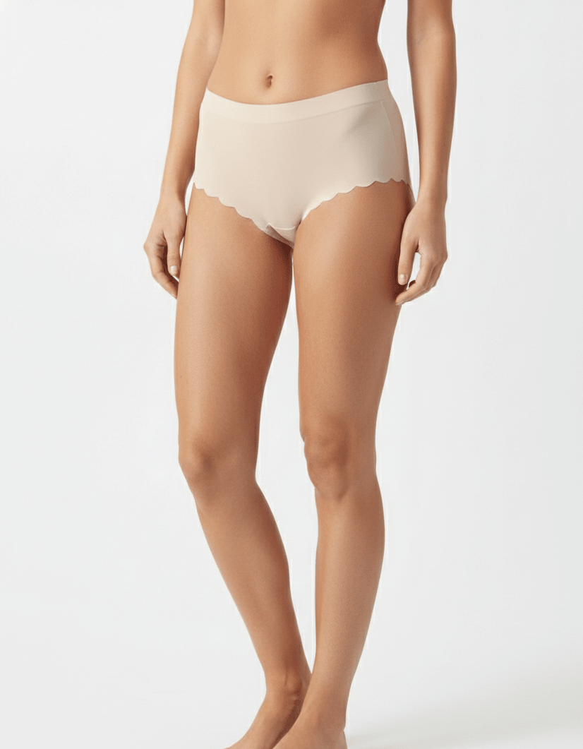 Seamless nude no-show panties with scalloped edges on a model against a white background.